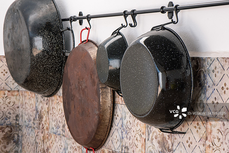 瓷砖墙上架子上的珐琅和金属平底锅图片素材