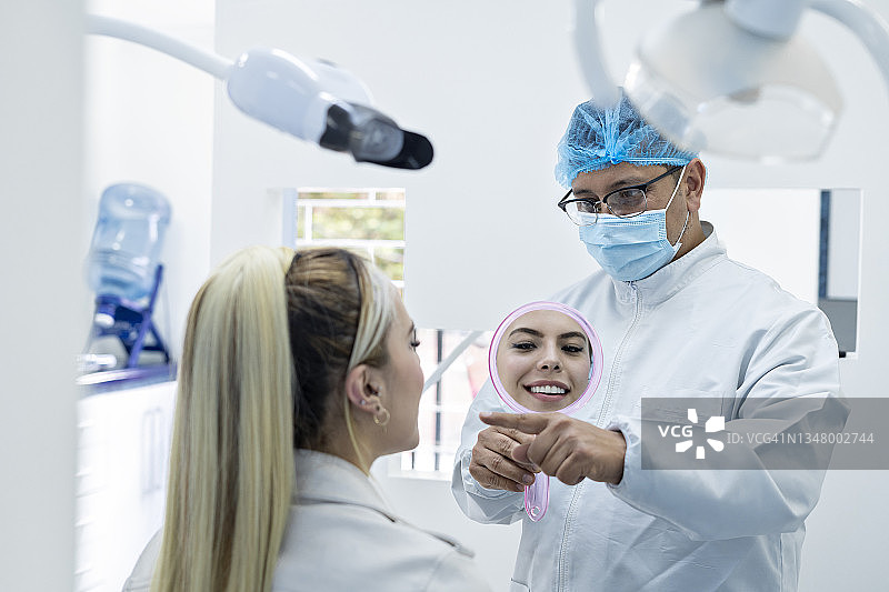 牙医用镜子向病人展示牙齿图片素材