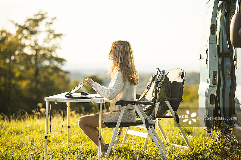 年轻女子在房车度假时使用笔记本电脑图片素材
