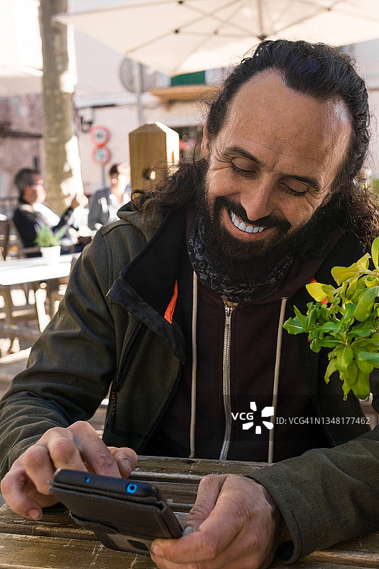 跳蚤市场摊主在酒吧露台上打字微笑的肖像图片素材