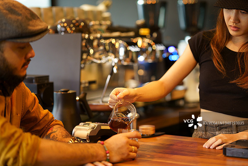 年轻女咖啡师为顾客倾倒黑咖啡图片素材