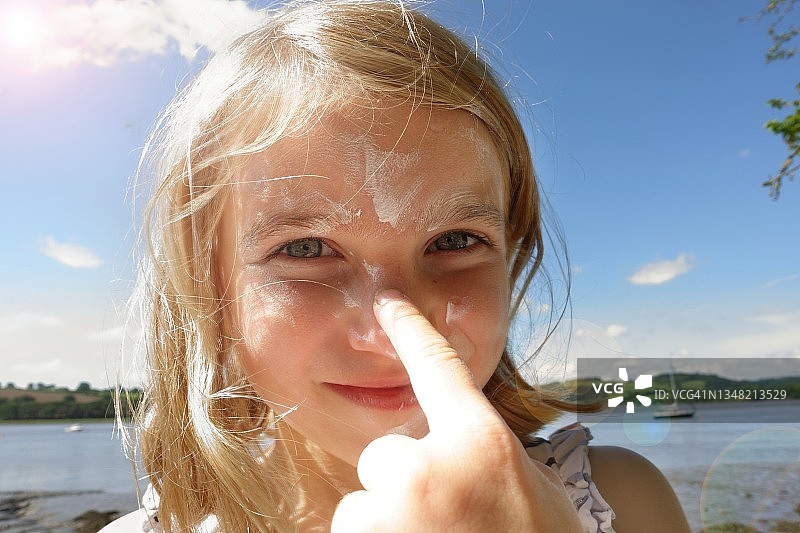 年轻女孩往脸上涂抹防晒霜图片素材