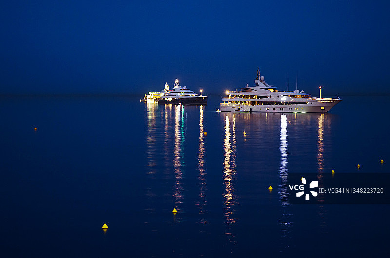 夜晚，两艘豪华超级游艇在海洋中反射着光芒图片素材
