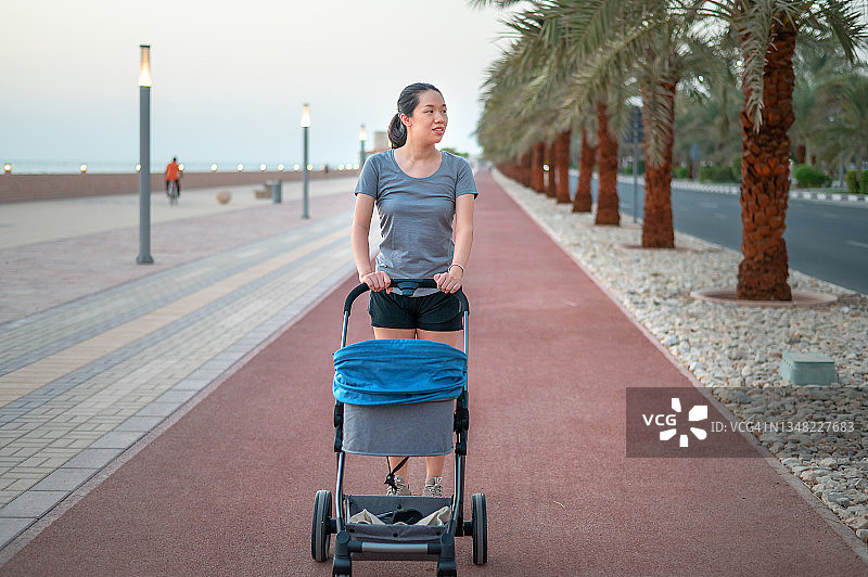 在跑道上推着婴儿车散步的健壮亚洲女性图片素材