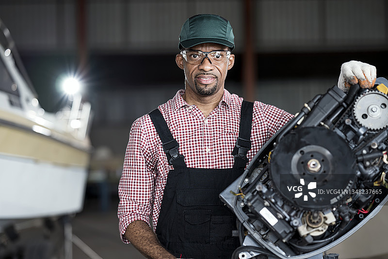 在码头和游艇服务中心修理舷外发动机的非洲裔船主图片素材