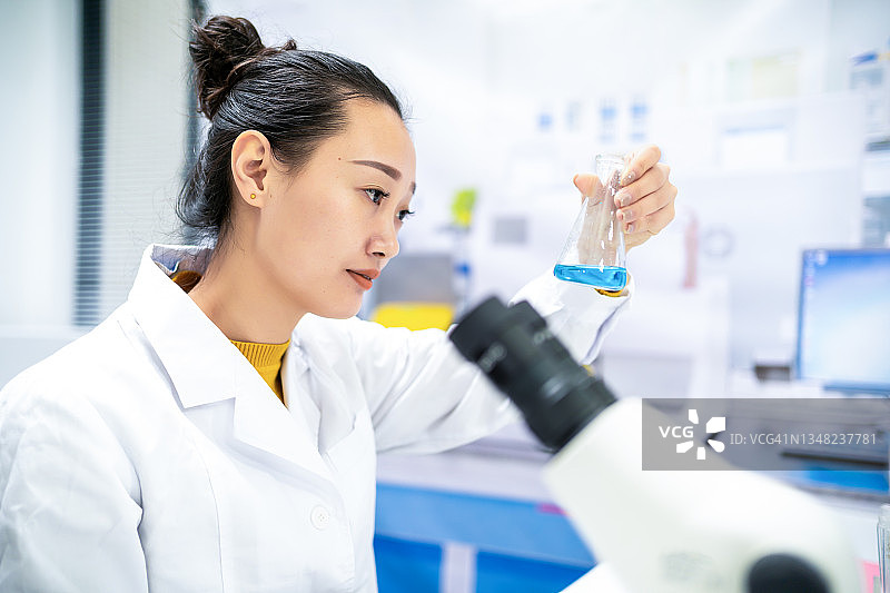 年轻的亚洲女科学家在实验室观察试剂图片素材