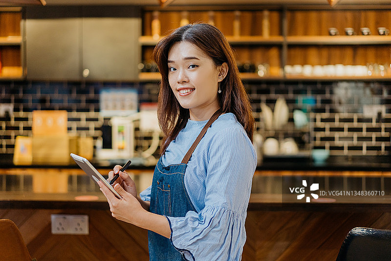 咖啡馆里手持平板电脑的女服务员图片素材