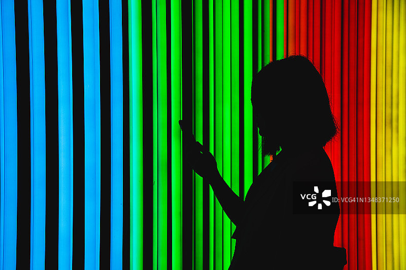 霓虹灯下使用手机的女人的轮廓图片素材