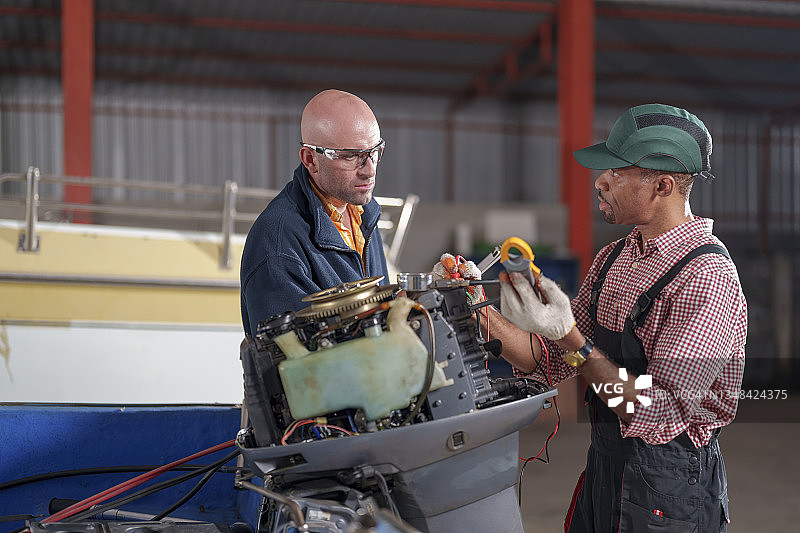 两名机械师在车间维修舷外发动机图片素材