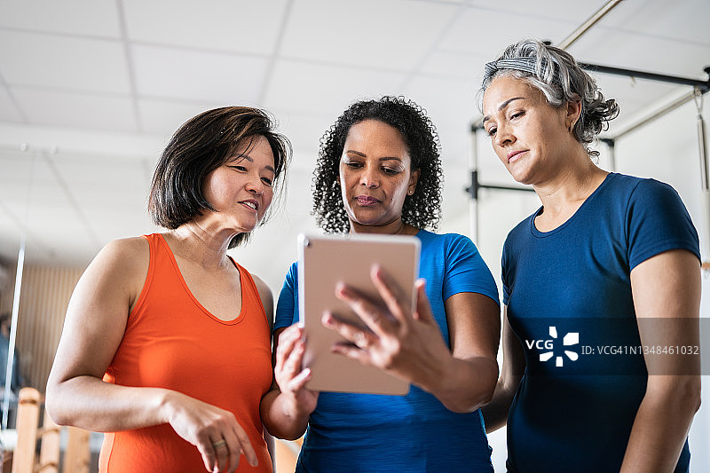 中年妇女在普拉提工作室看平板电脑图片素材