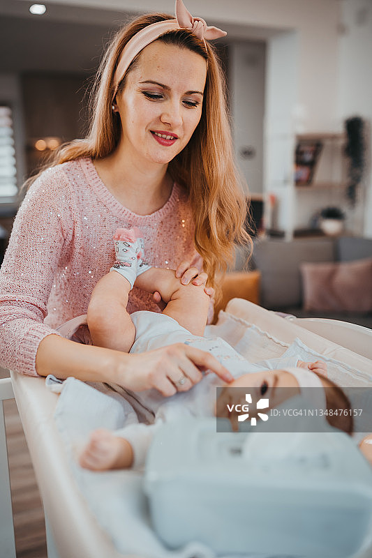 母亲为婴儿换尿布图片素材