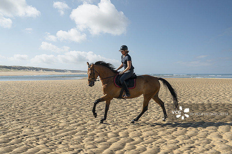 年轻女子在法国大西洋海滩骑马图片素材