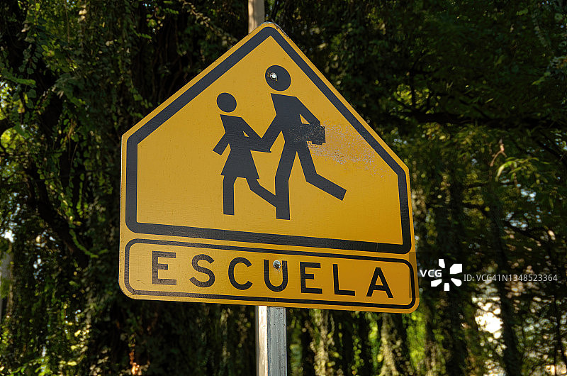 西班牙语道路警告标志，指示“Escuela”[学校]和学童过马路图片素材
