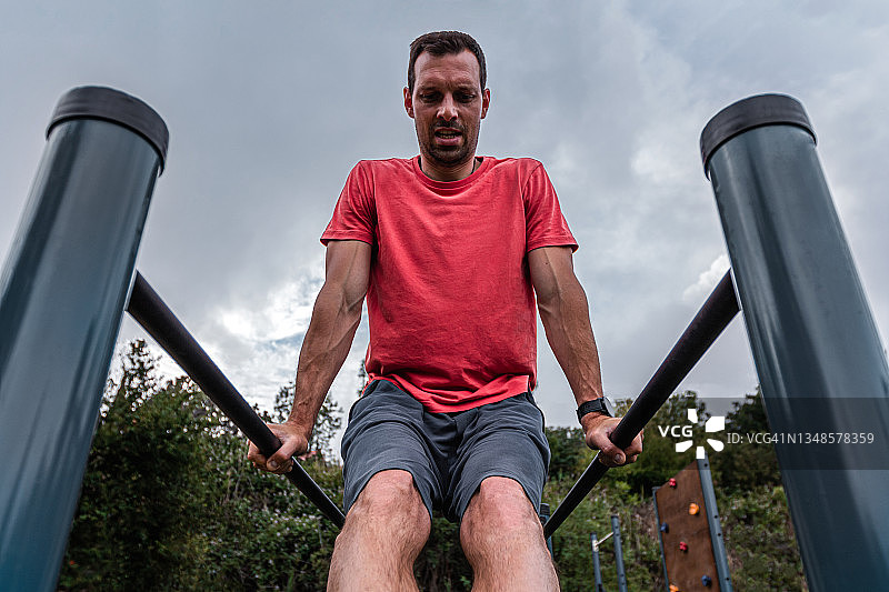 在双杠上做俯卧撑的健壮男人图片素材