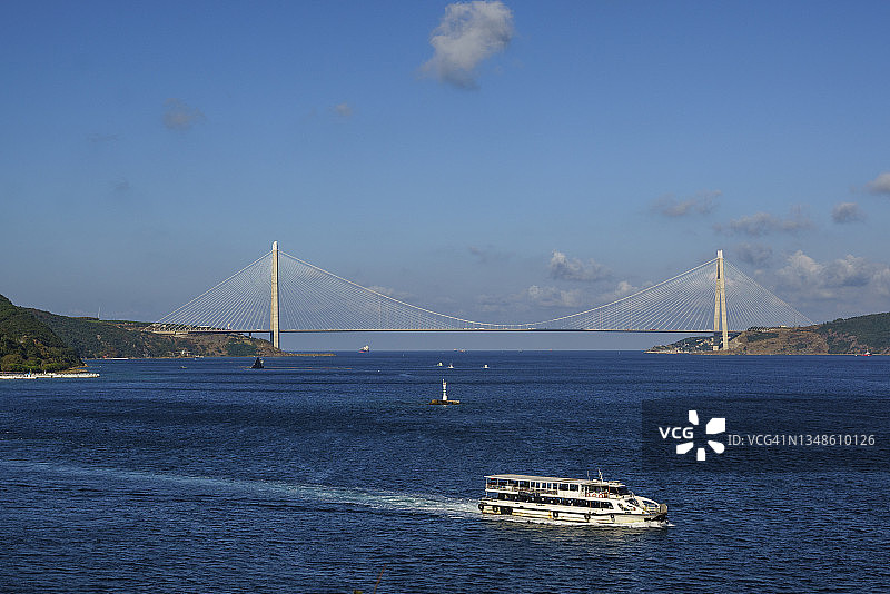 在马尔马拉海上航行的渡轮，背景是土耳其伊斯坦布尔的亚武兹苏丹塞利姆大桥图片素材