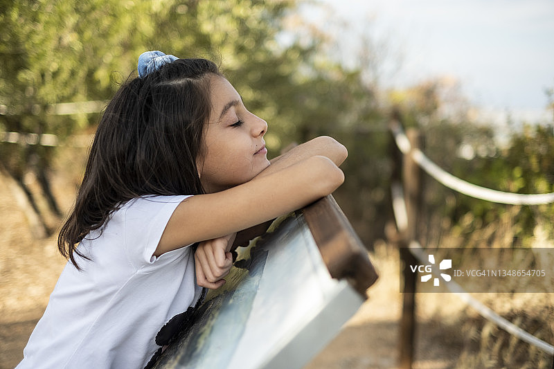 在自然公园里，女孩在指示性海报上休息，上面介绍了该地区的动植物物种图片素材