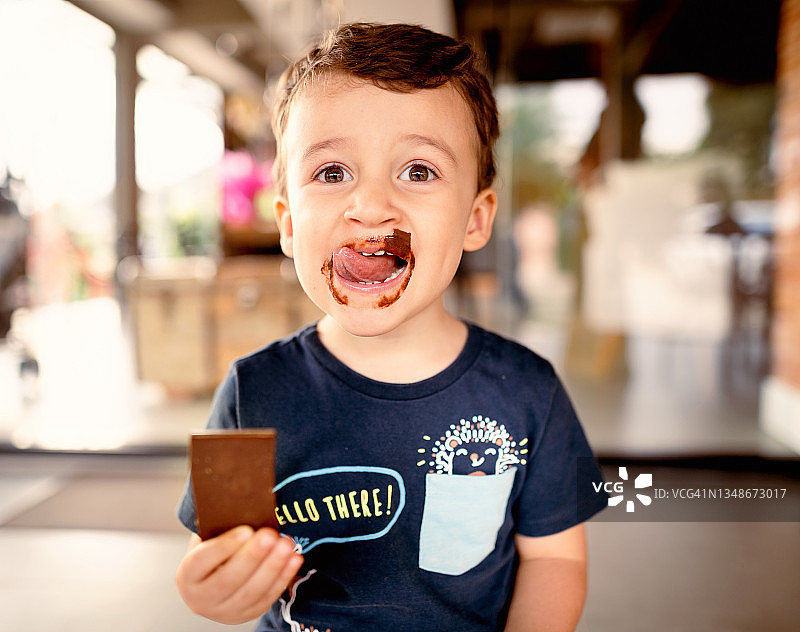 微笑的小男孩舔着脸上的巧克力图片素材