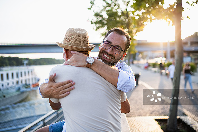 在户外小镇拥抱中年儿子的老年男人图片素材