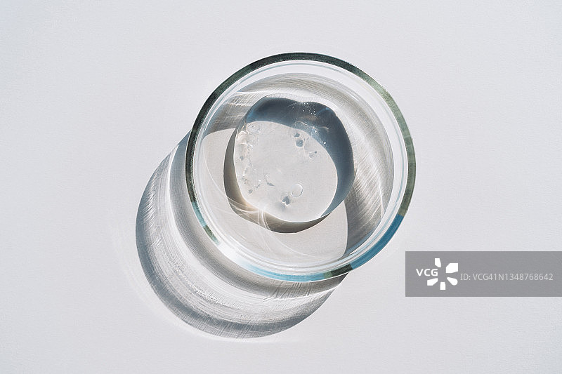 灰色背景的培养皿中透明凝胶，化妆品实验室研究概念，扁平风格摄影图片素材