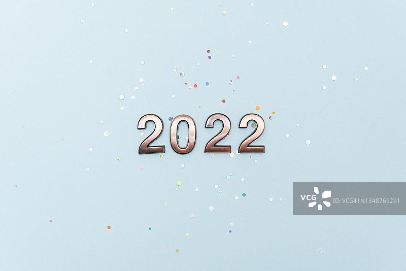 2022新年庆祝活动。箔纸气球数字2022和蓝色背景上的闪光星星。平面布局图片素材