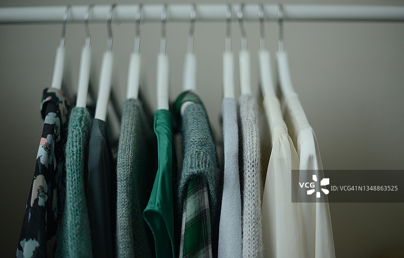 挂在白色衣架上的绿色毛衣和衬衫图片素材