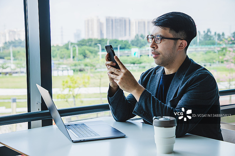 使用手机和笔记本电脑工作的亚洲商人图片素材