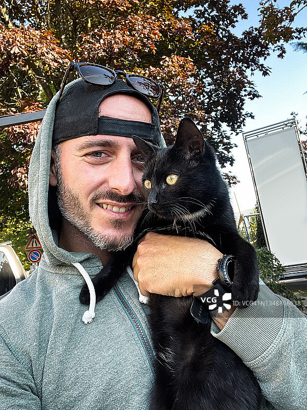 抱着黑猫的快乐男人图片素材