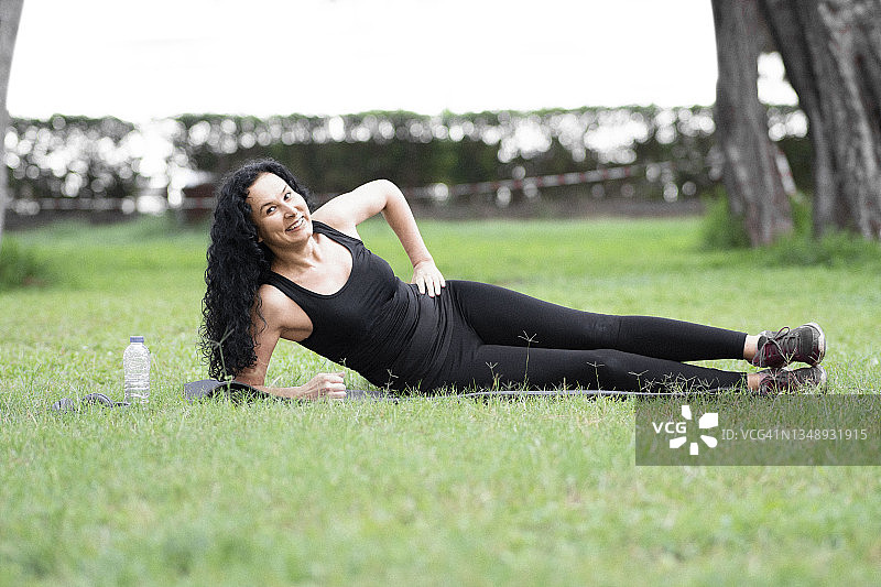 年轻女人在公园里做侧平板支撑的镜头图片素材