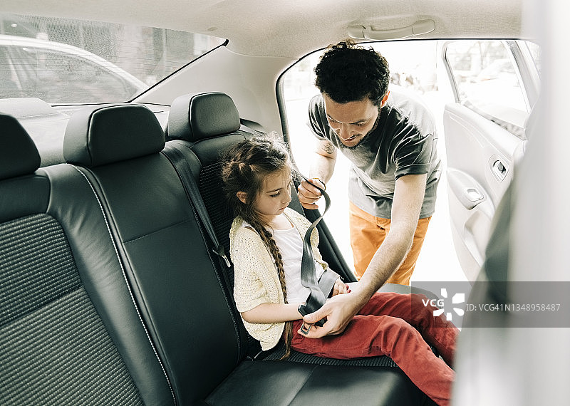 旅途前父亲将女儿安全地固定在汽车后座上图片素材