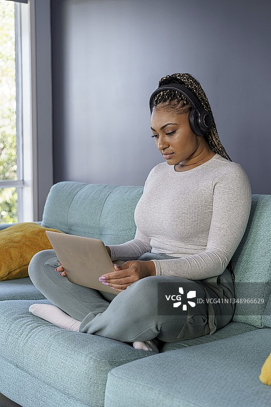 女人在家放松时使用平板电脑和耳机图片素材