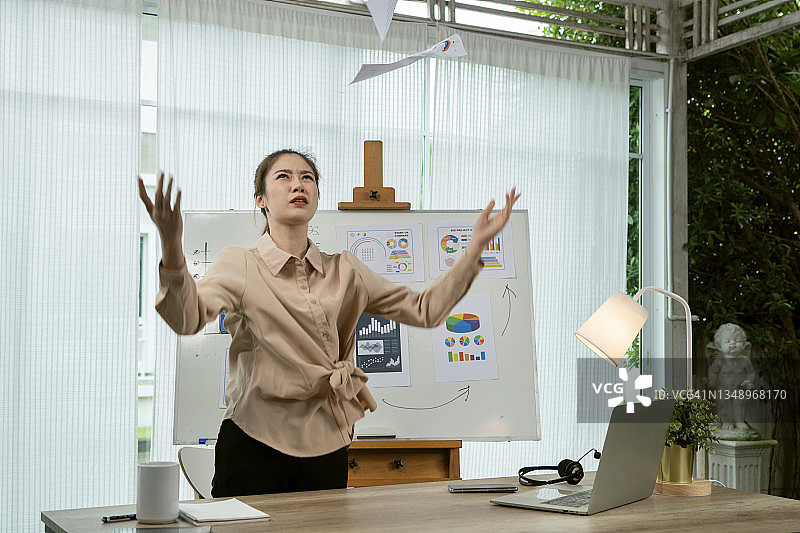 生气的亚洲女性在家居办公室里扔文件图片素材