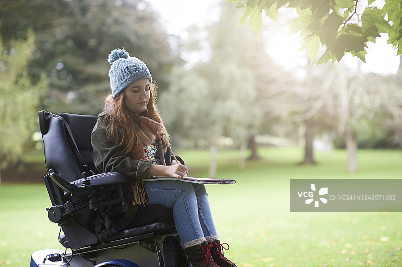 在秋季公园的画板上绘画的残疾女艺术家图片素材