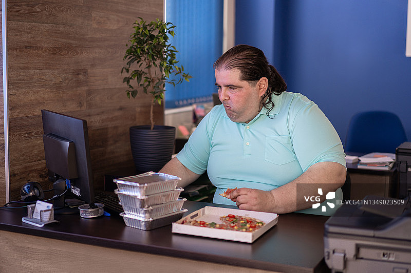 忙碌的男士一手拿着午餐，一手放在键盘上图片素材