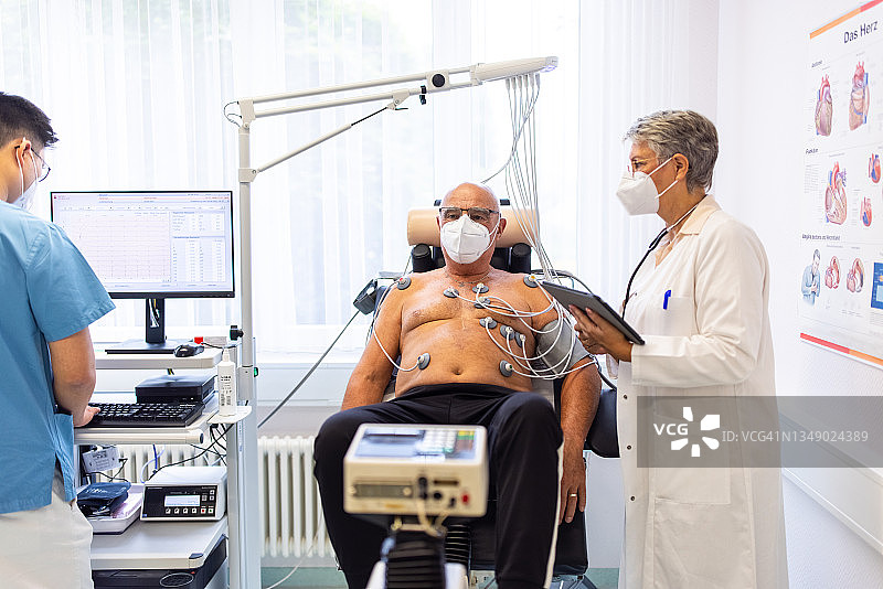 诊所治疗期间，心脏科医生与老年患者在心电图自行车上图片素材