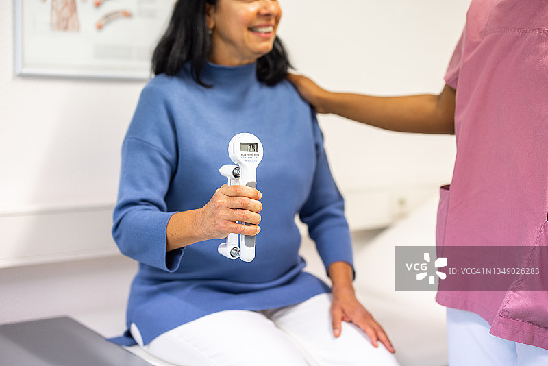 中年妇女使用握力计测试她的最大握力图片素材