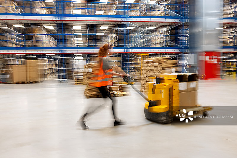 仓库中搬运箱子的女人的动态模糊图片素材