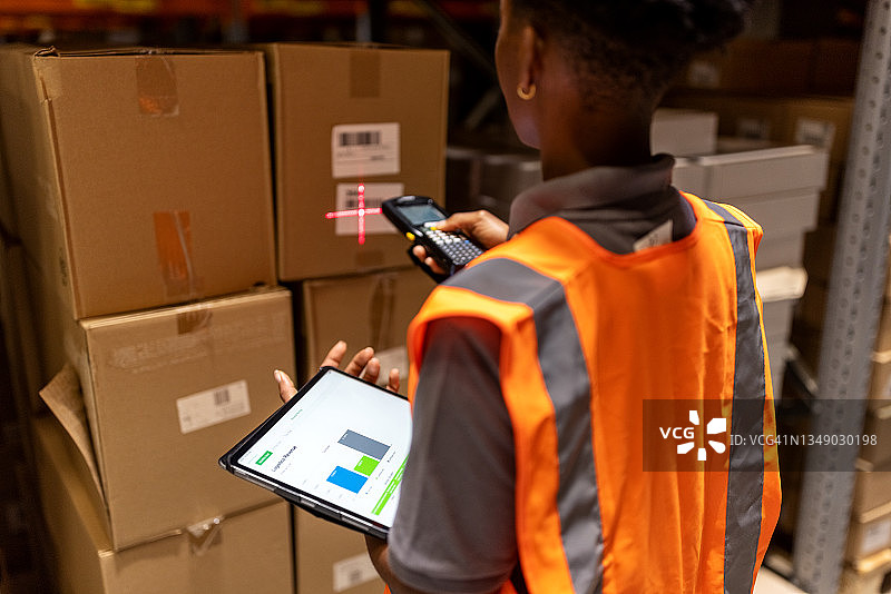 仓库工人在储物架上扫描箱子图片素材