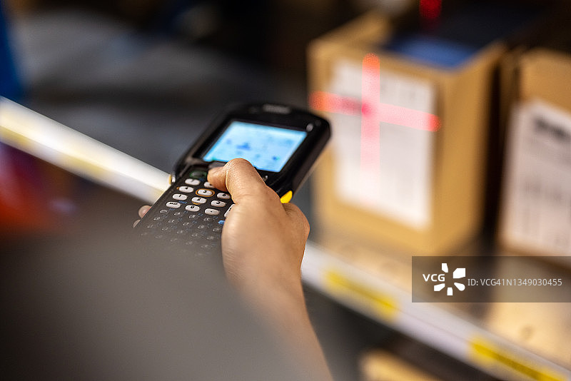 仓库工人扫描货架上的箱子特写图片素材