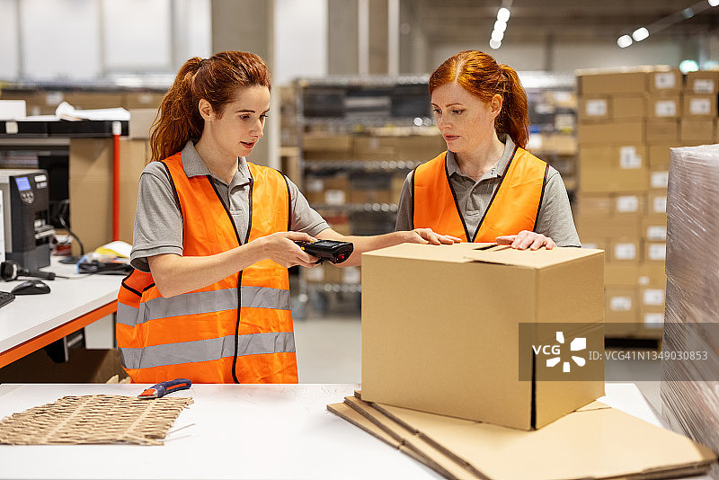 两位女士在配送仓库扫描送货箱标签图片素材