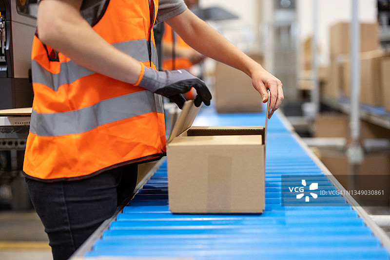 女仓库工人在传送带上封箱特写图片素材