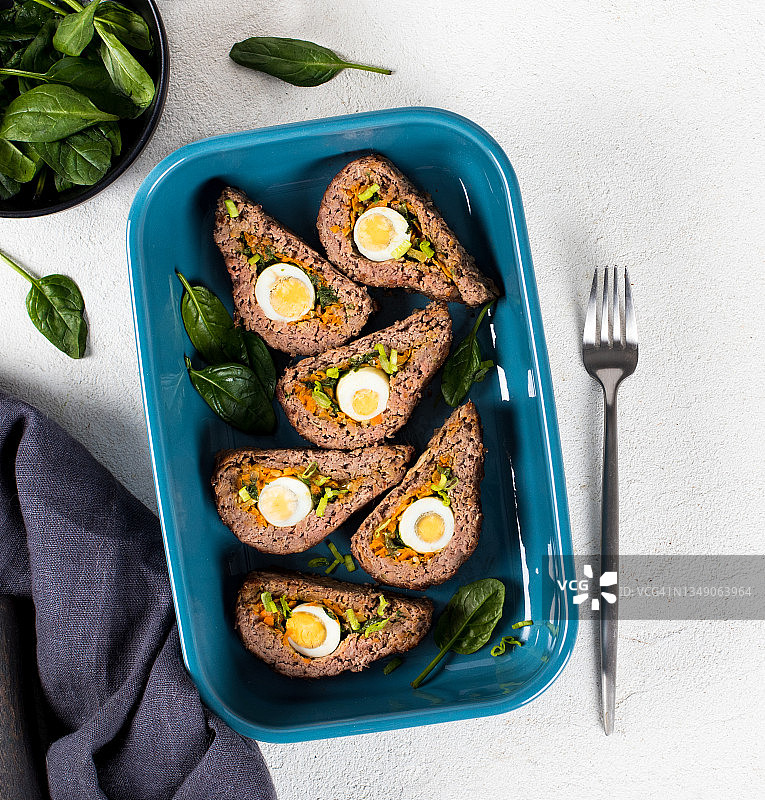 陶瓷烤盘中配鹌鹑蛋、胡萝卜、洋葱和菠菜的牛肉卷图片素材