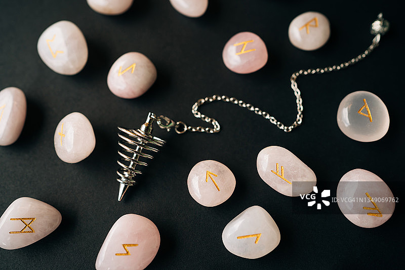 银色探测摆和玫瑰石英符文，黑色背景，魔法神秘仪式概念，扁平风格宏摄影图片素材