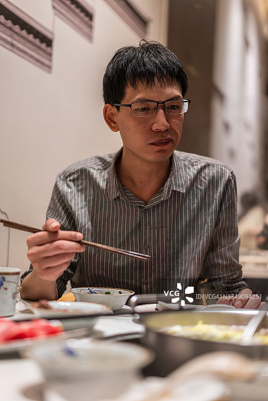 亚洲男人在牛肉火锅店用餐图片素材