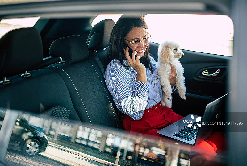 在车内使用手机和笔记本电脑的女商人图片素材