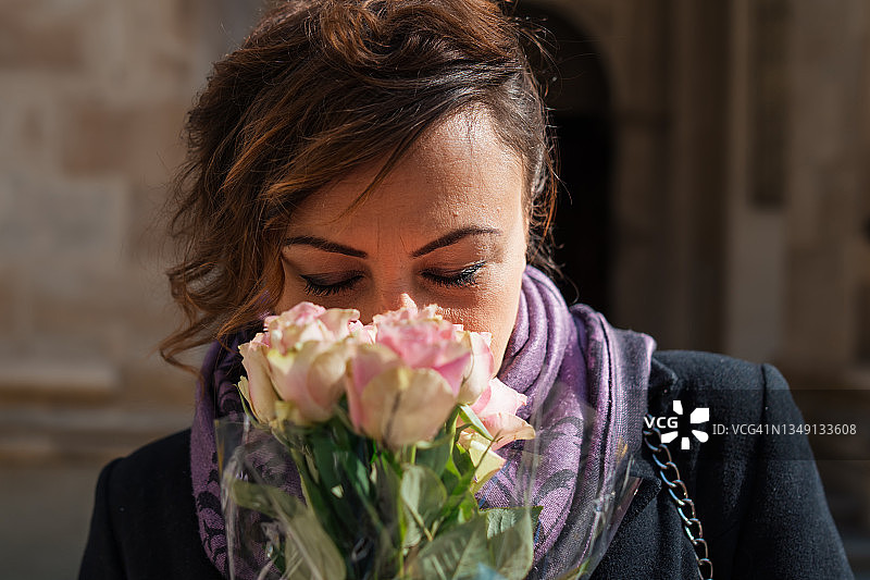 穿着优雅的年轻女子闻着玫瑰花束图片素材