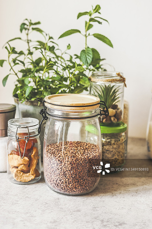 厨房桌上玻璃罐中的荞麦，配料和香草，白色墙面背景图片素材