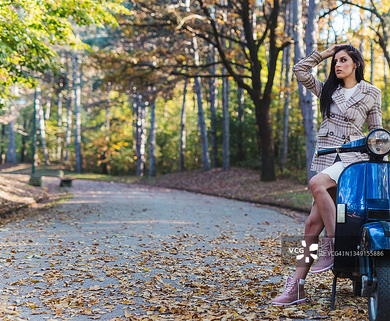 职场女性坐在摩托车上享受秋日图片素材