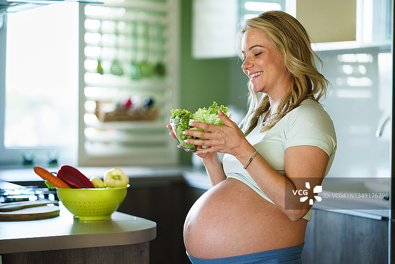 孕妇在厨房手捧一碗新鲜蔬菜图片素材