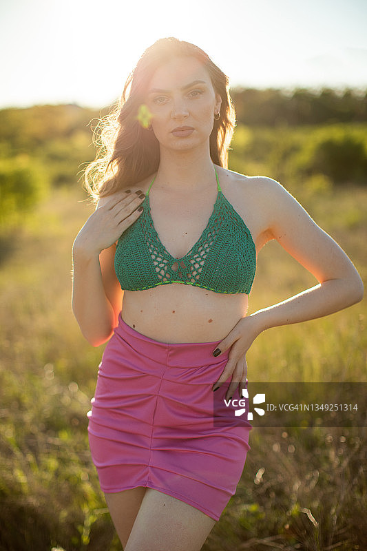 一位穿着钩针上衣的年轻女子在夏日田野里的肖像图片素材