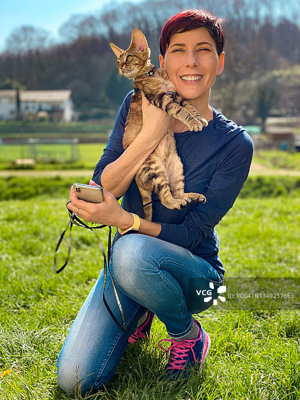 德文雷克斯猫和女主人在公园里散步，在美好的一天合影（库存照片）图片素材